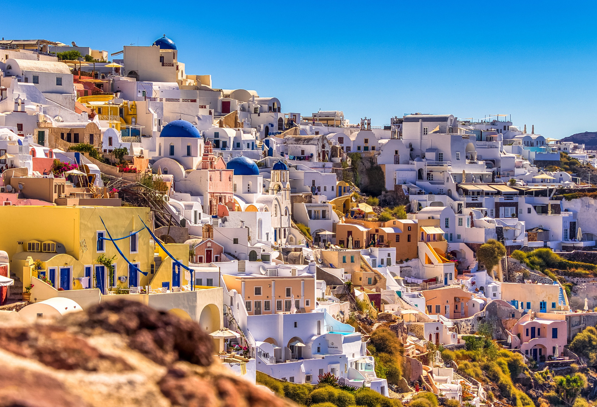 Valkoisia ja sinisiä kupolikirkkoja sekä taloja, sininen taivas ja aurinkoiset terassit Santorinassa. Santornin, Greece. Kreikka.