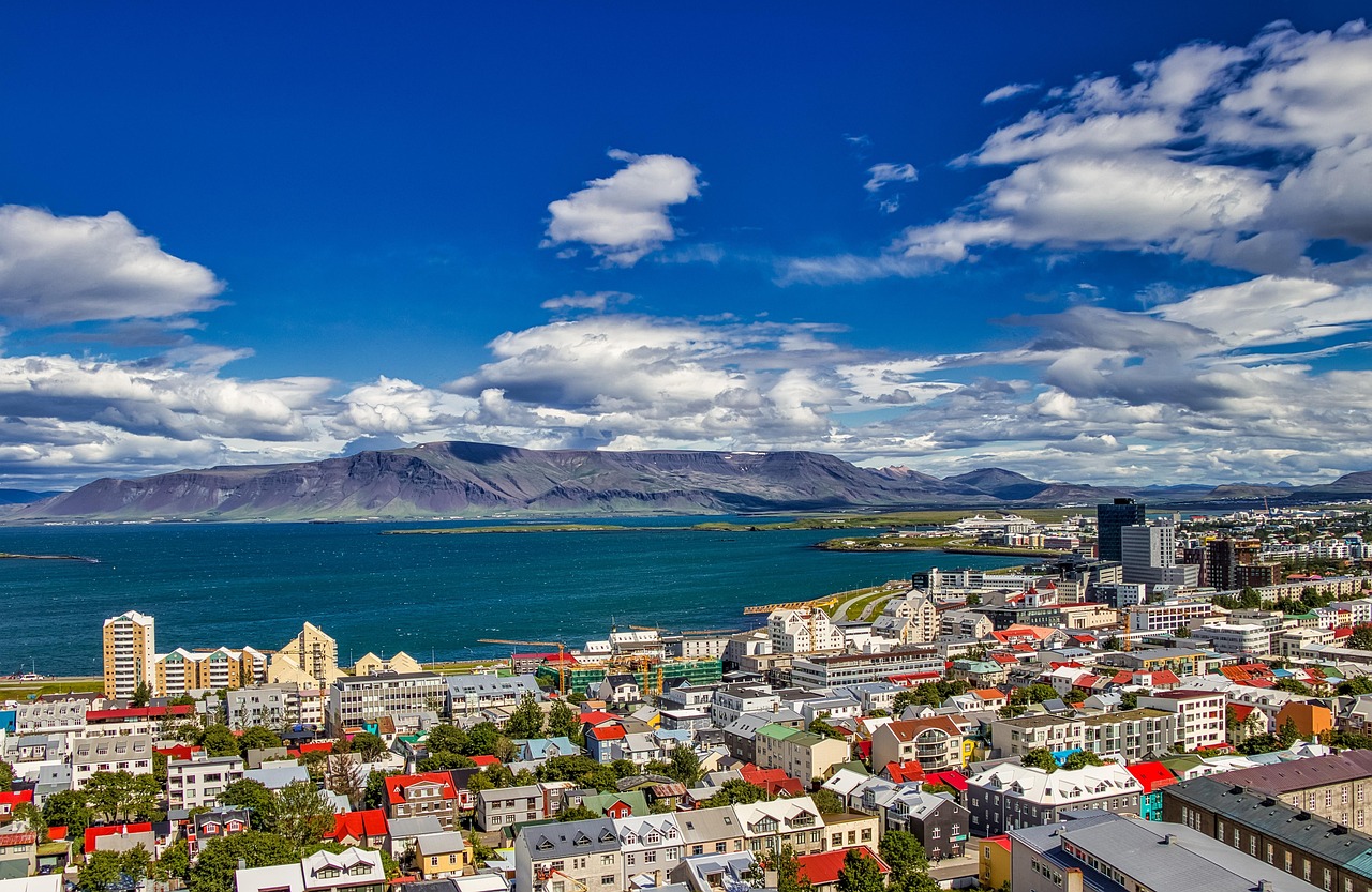 Reykjavík on Islannin kaunis ja kompakti pääkaupunki.
Värikkäitä taloja ja satama meren rannalla, taustalla vuorijono ja sininen taivas pilvineen.