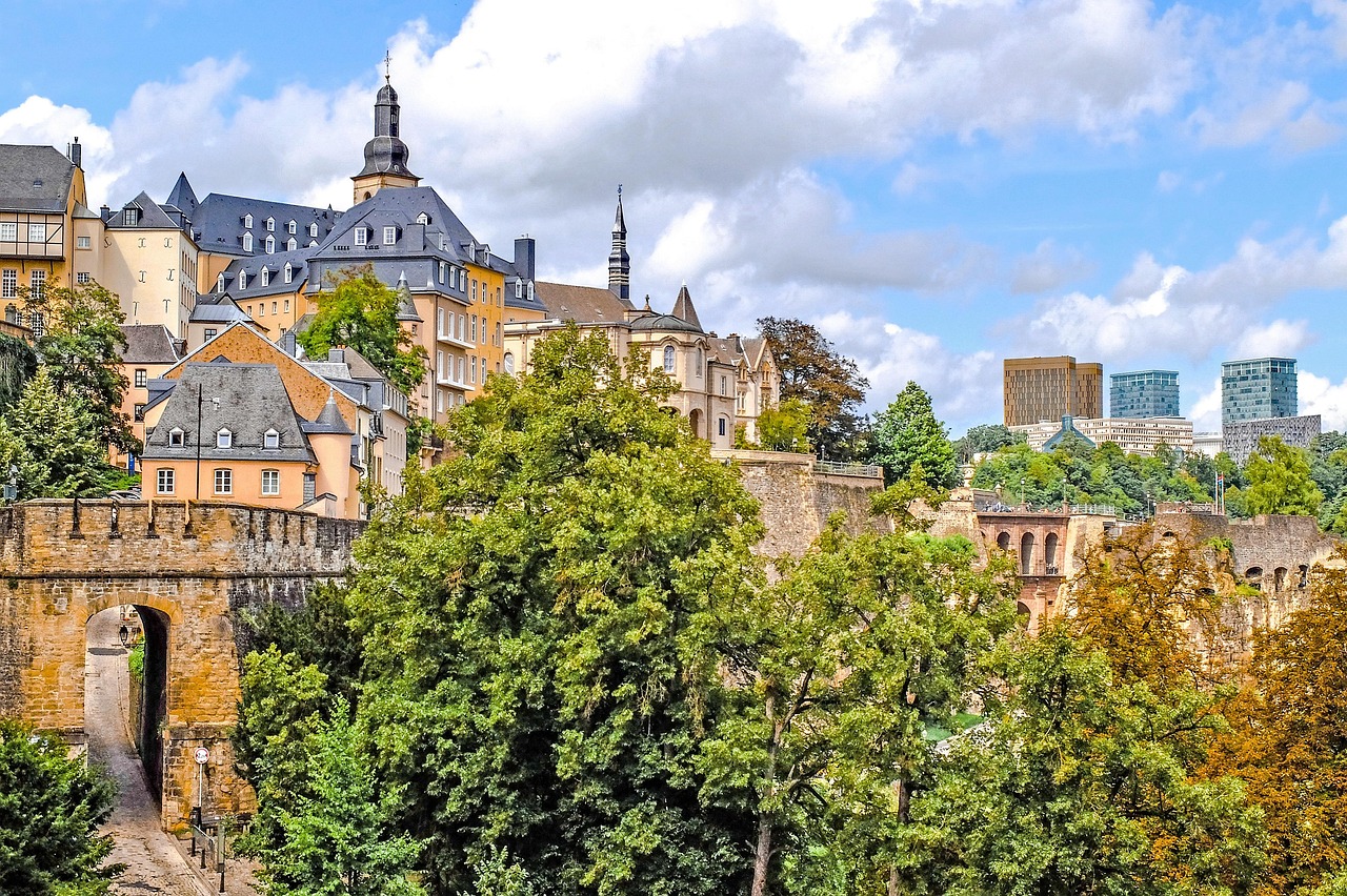 Kaunis, historiallinen Ville Haute. Luxemburgin vanhakaupunki. Värikkäitä vanhoja rakennuksia ja kirkontorneja, puiden peittämä jokiranta sekä taustalla modernit pilvenpiirtäjät.