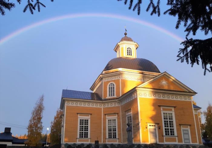 Vetelin kirkko on rakennettu vuonna 1843.
Kirkko auringonlaskun aikaan, kultainen kupoli ja kaari taivaalla, puiden oksat kehystävät.
