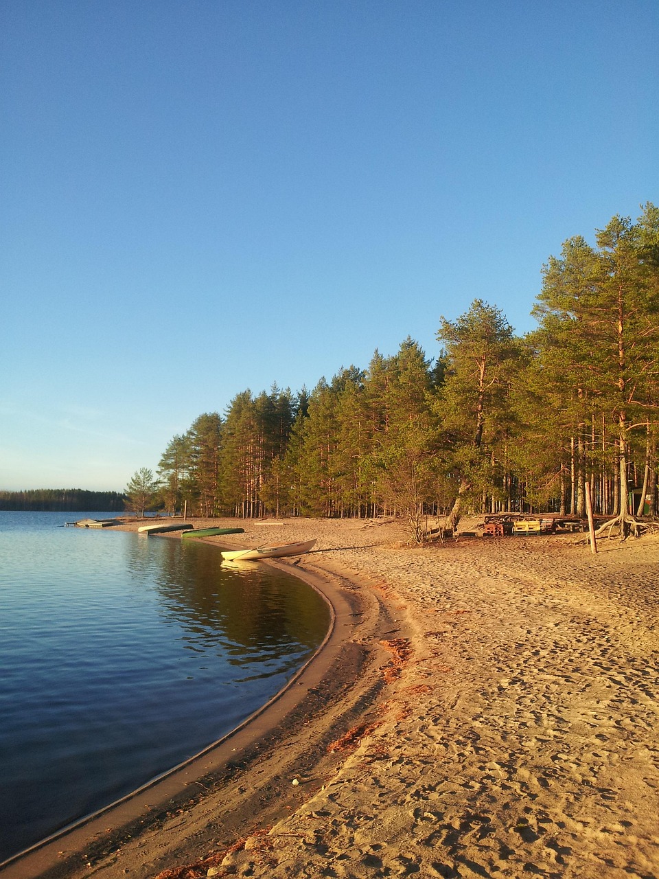 Vaalan kunnan alueella on yli 100 kilometriä hiekkarantoja.
Hiekkaranta järven rannalla, mäntymetsä taustalla ja useita veneitä vedessä.