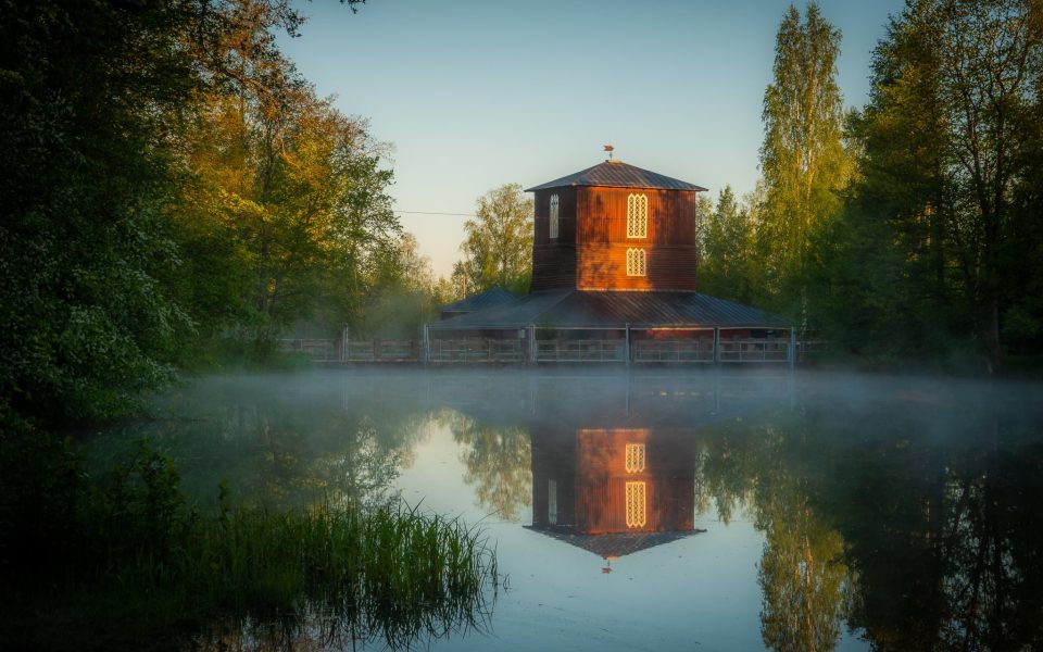 Leineperin ruukki. Kuva: Visit Satakunta
Punainen puinen rakennus heijastuu sumuisessa järvessä, ympärillä koivut ja lehtipuut auringonlaskun aikaan.
