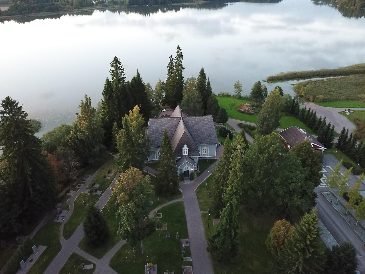 Vuonna 1734 rakennettu Tuusulan kirkko sijaitsee kauniin Tuusulanjärven rannalla.
Ilmakuva järven rannalla olevasta omakotitalosta, piha-alueesta, puista ja harmaasta tiestä.