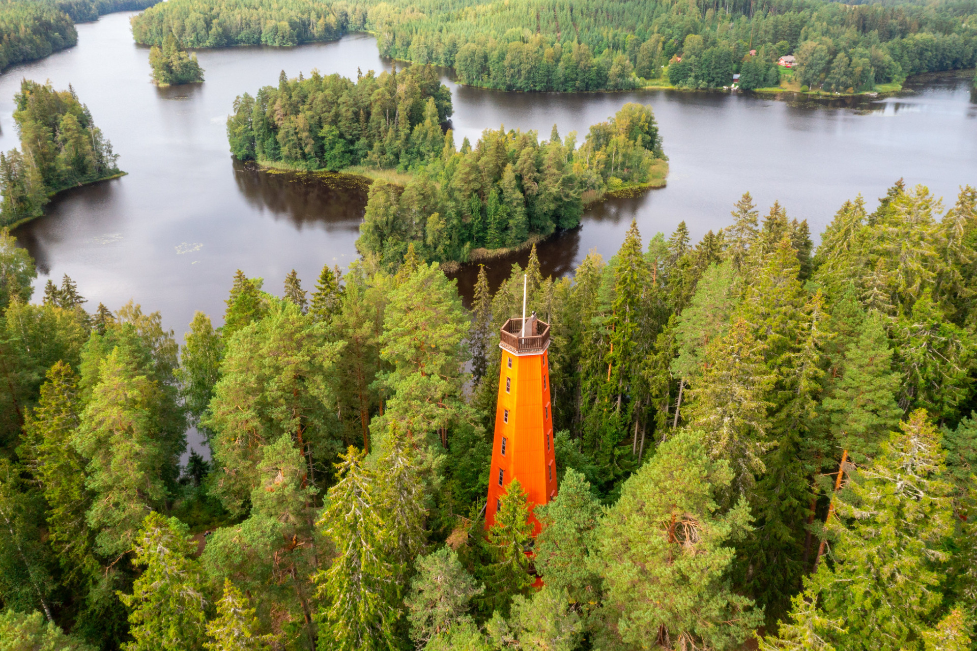 Kaukolanharjun näkötornista näet kauniit Kanta-Hämäläiset maisemat.
Oranssi näkötorni metsän keskellä järven ja saarten yllä, vihreää kasvillisuutta ja rauhallinen rantamaisema.