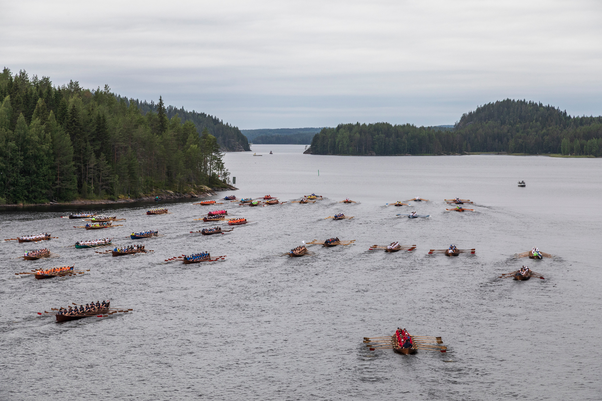 Sulkavan suursoudut on kesäisin suosittu tapahtuma.
Useita soutuveneitä ja kilpailijoita järvellä, metsärannat taustalla ja harmaa pilvinen taivas.