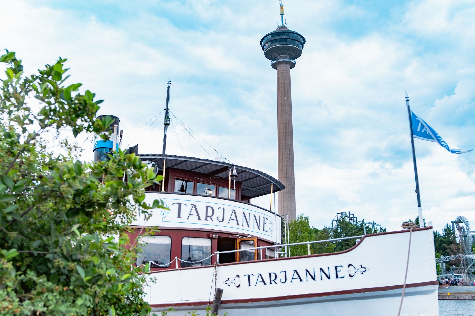 Höyrylaiva Tarjanne risteilee kesäisin Tampereen ja Ruoveden välillä.
Punainen laiva “TARJANNE” ja korkea televisiotorni taustalla, sininen lippu oikealla, vihreää puustoa edessä.