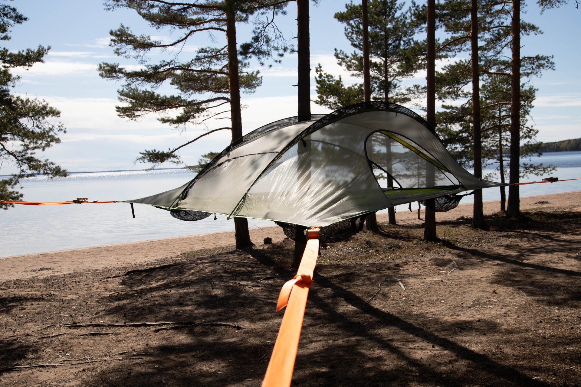 Huuhanranta on 1,5 kilometriä pitkä Saimaan upea hiekkaranta.
Rantaleirillä teltta auki mäntymetsän keskellä, järvimaisema taustalla ja oranssi kiinnitysnaru etualalla.