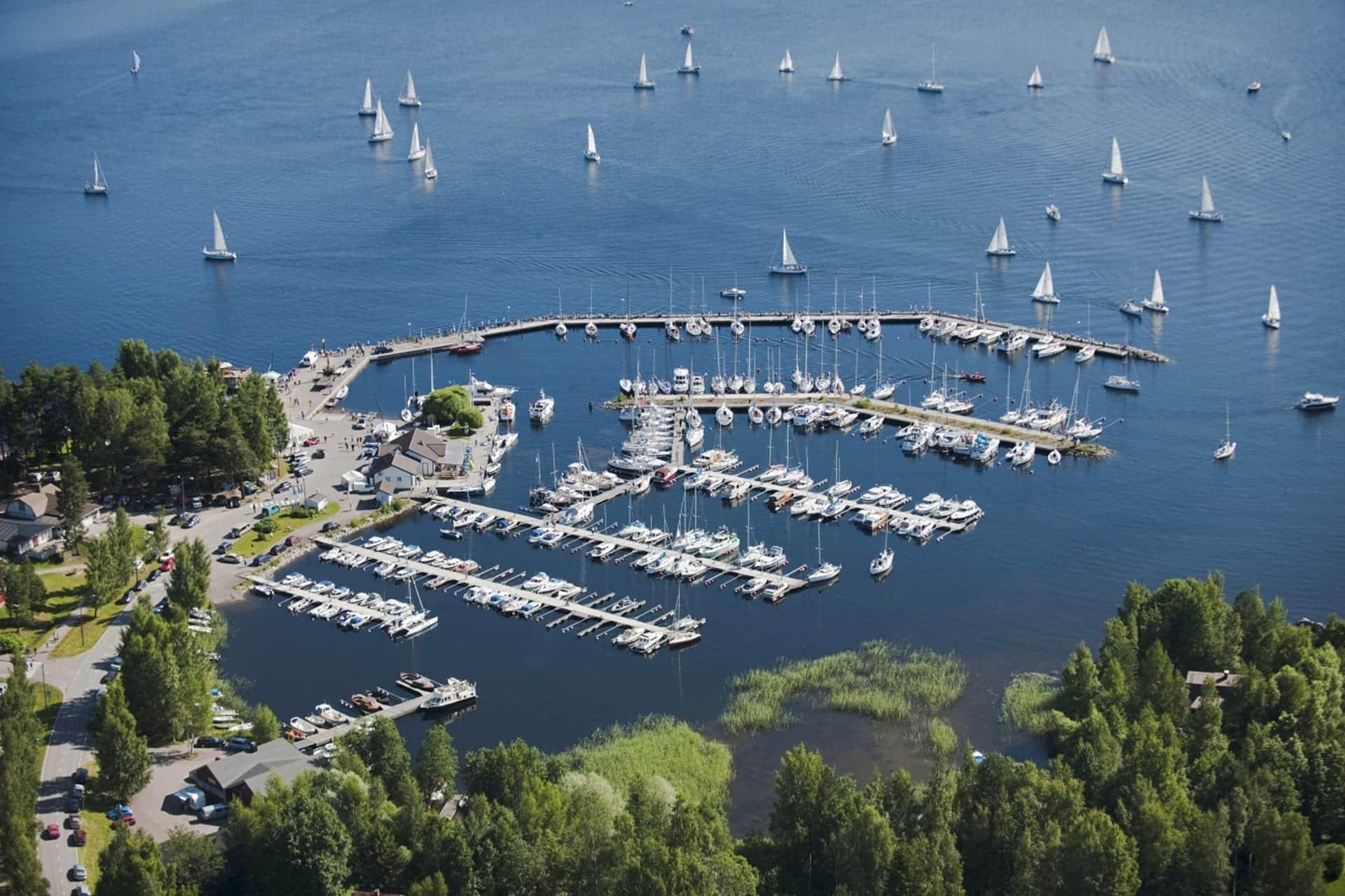 Padasjoen satama Päijänteen rannalla.
Ilmakuva satamasta, jossa lukuisia purjeveneitä ja moottoriveneitä laitureilla sinisellä järvellä.