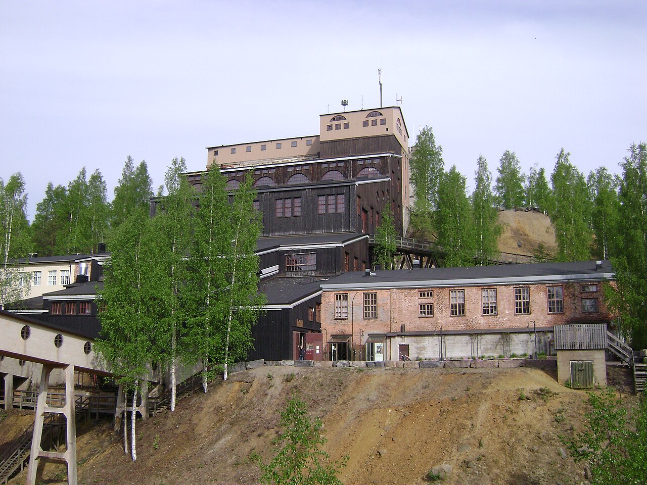 Vanha kaivos on Outokummun tunnetuin nähtävyys.
Tiilinen tehdasrakennus ja korkea torni, ympärillä koivuja ja sorainen rinne, taustalla vaalea taivas.