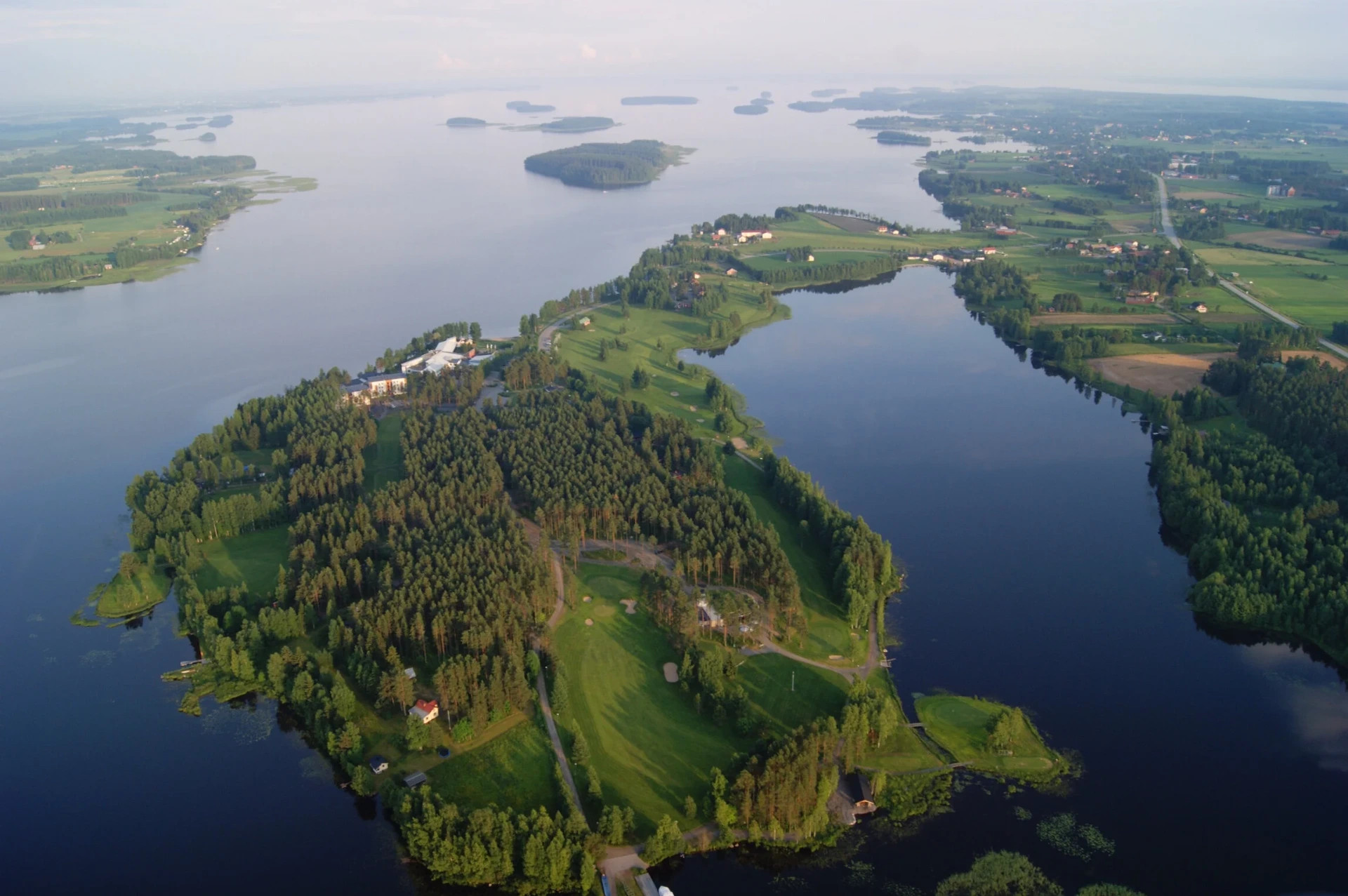 Kraatterijärvi Lappajärvi.
Ilmakuva leveästä joesta, metsäsaarista ja niityistä, pienistä rakennuksista sekä siltojen ja teiden verkostosta.