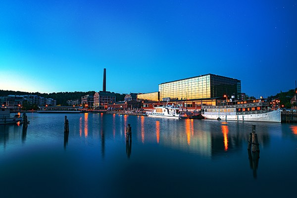 Lahden satama ja Sibeliustalo Vesijärven rannalla
Sininen iltataivas, satama ja heijastukset, laivoja sekä suuri rakennus ja korkea torni rannalla.